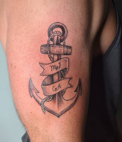 Tatuaje de ancla sombreada con cuerda enrollada y cintas que llevan las letras "M y J" y "C y A".